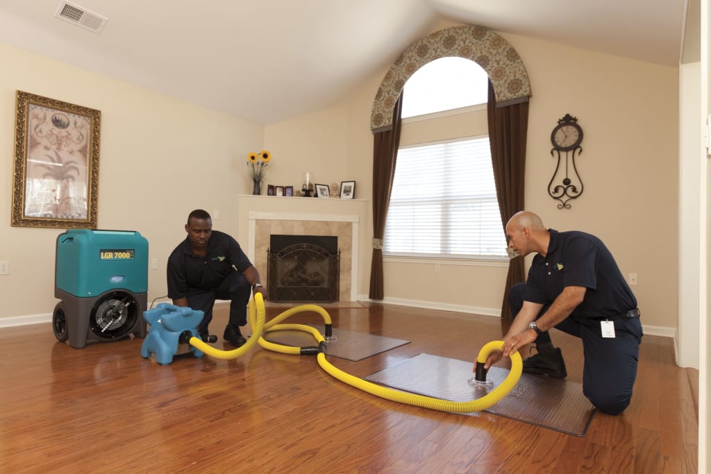 Technicians using drying equipment on a wood floor